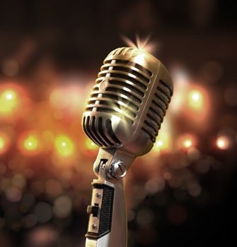 Classic silver 1950s microphone with a reflective glimmer, on a warm glowing bokeh background.